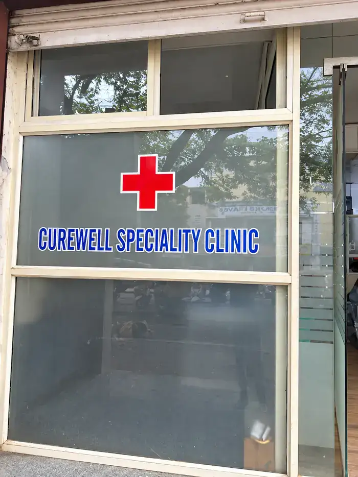 Glass entrance door with a red cross and the words Curewell Speciality Clinic